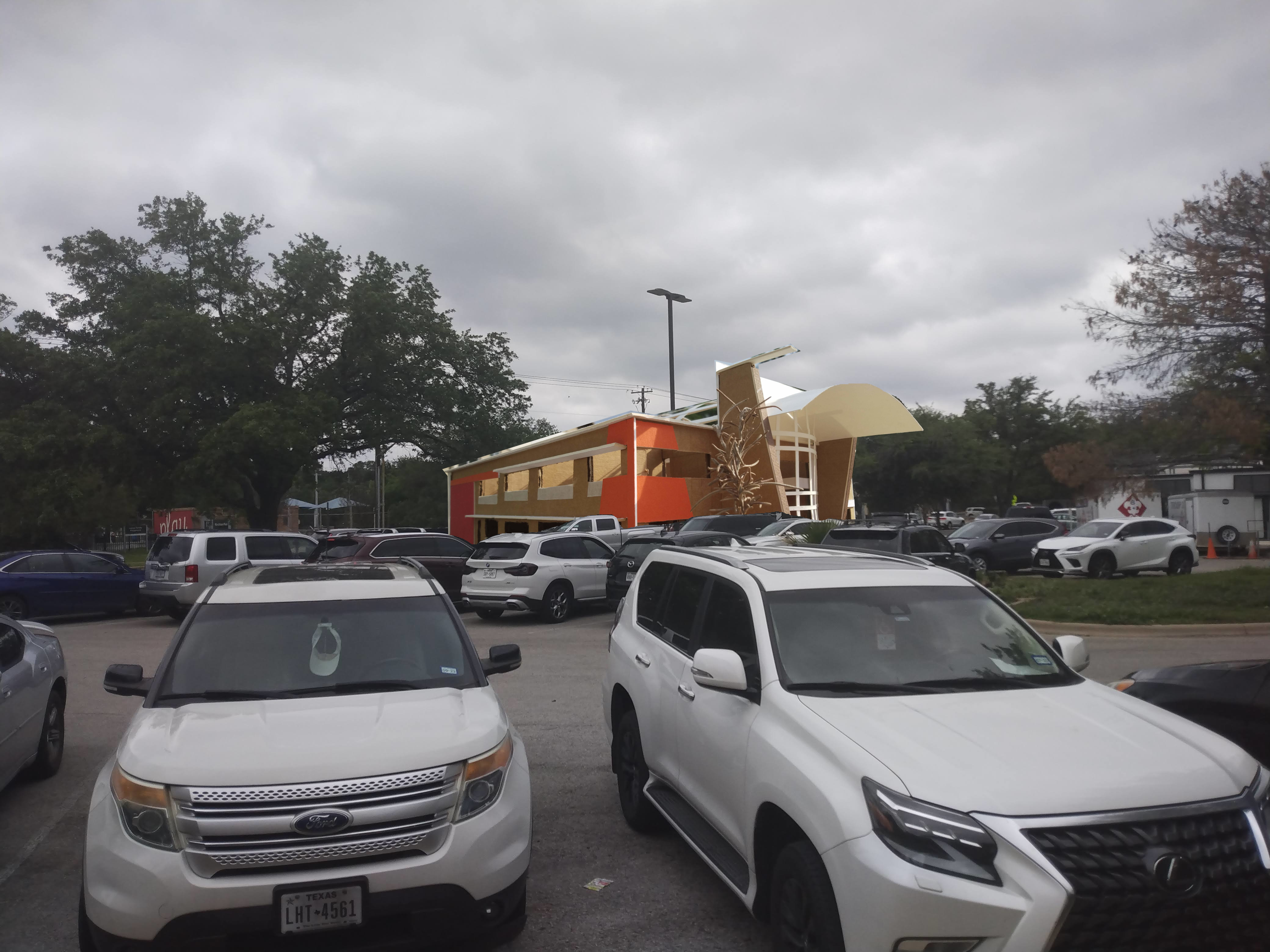 a photoshopped image of the cardboard model standing to scale in the background of a real parking lot