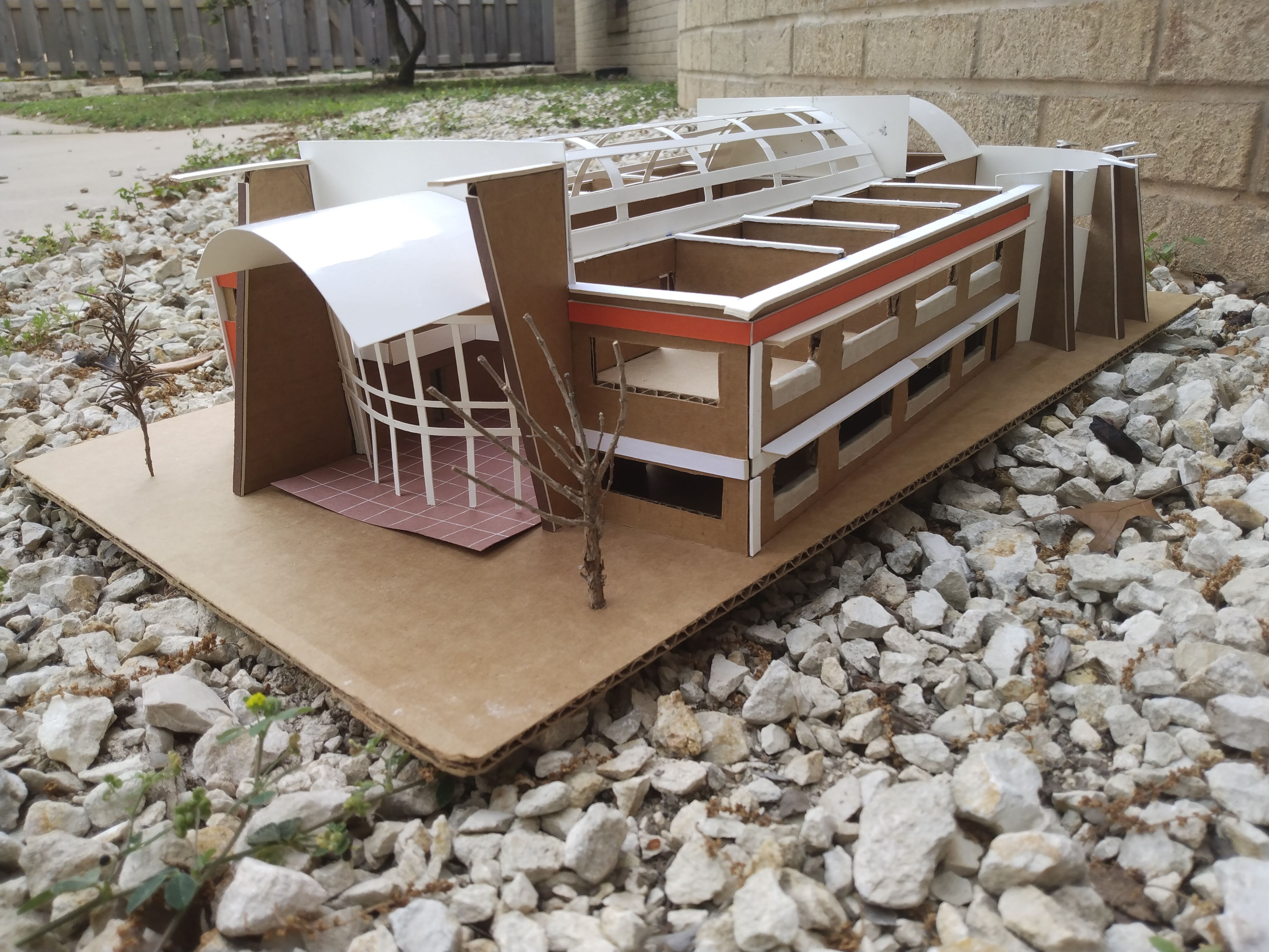 a cardboard mockup of a school sitting on top of gravel, featuring colorful elements and intricate details